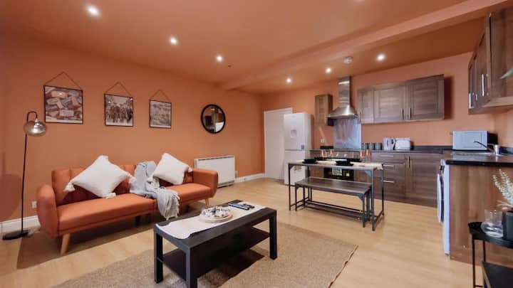 Opustite se na našem udobnom narančastom kauču u ovom živopisnom životnom prostoru.