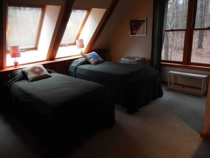 Dve extra dlhé samostatné postele je možné poskladať do postele veľkosti King.  Šikmý pohľad na jazero cez strešné okná.  Strešné okná majú rolety a dajú sa otvárať.