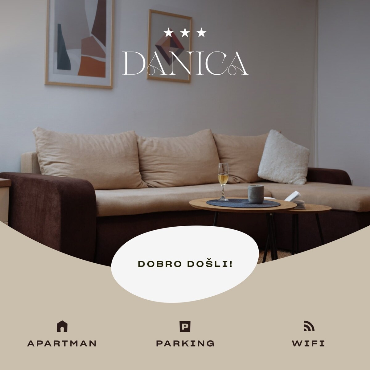 A comfortable sofa with neutral-colored cushions and a compact coffee table is featured in a cozy living area. Framed artwork hangs on the wall, and a glass of drink sits atop the table, suggesting a welcoming space for relaxation.
