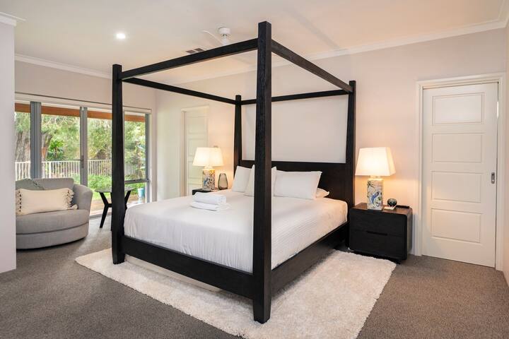 Ampia camera da letto principale con un lussuoso letto matrimoniale grande a baldacchino, lampade da comodino, TV a schermo piatto a parete e soffice pavimento in moquette. Perfetto per un rifugio riposante con stile e comfort.