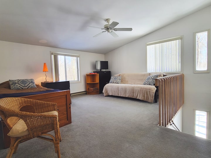 Upper level living room has two sleeping beds and tv