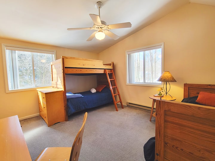 This bedroom has a twin size single bed, twin size bunk bed, closet and a workstation with chair