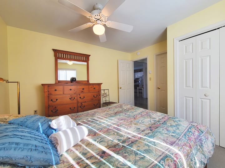 This bedroom has a queen size bed and a dresser with mirror