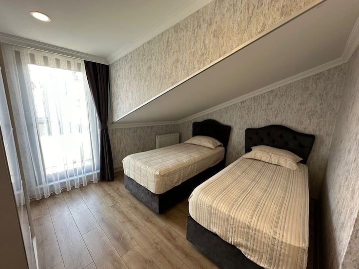 Chumba cha kulala cha kisasa chenye vitanda viwili vya mtu mmoja huko Sisli, Istanbul. Inatoa mazingira ya amani ya kulala na muundo wake angavu na wenye nafasi kubwa. Inatoa sehemu ya kukaa yenye starehe na mapambo yake maridadi na mpangilio unaofaa. Sehemu ya kukaa yenye starehe na maridadi katikati ya jiji.