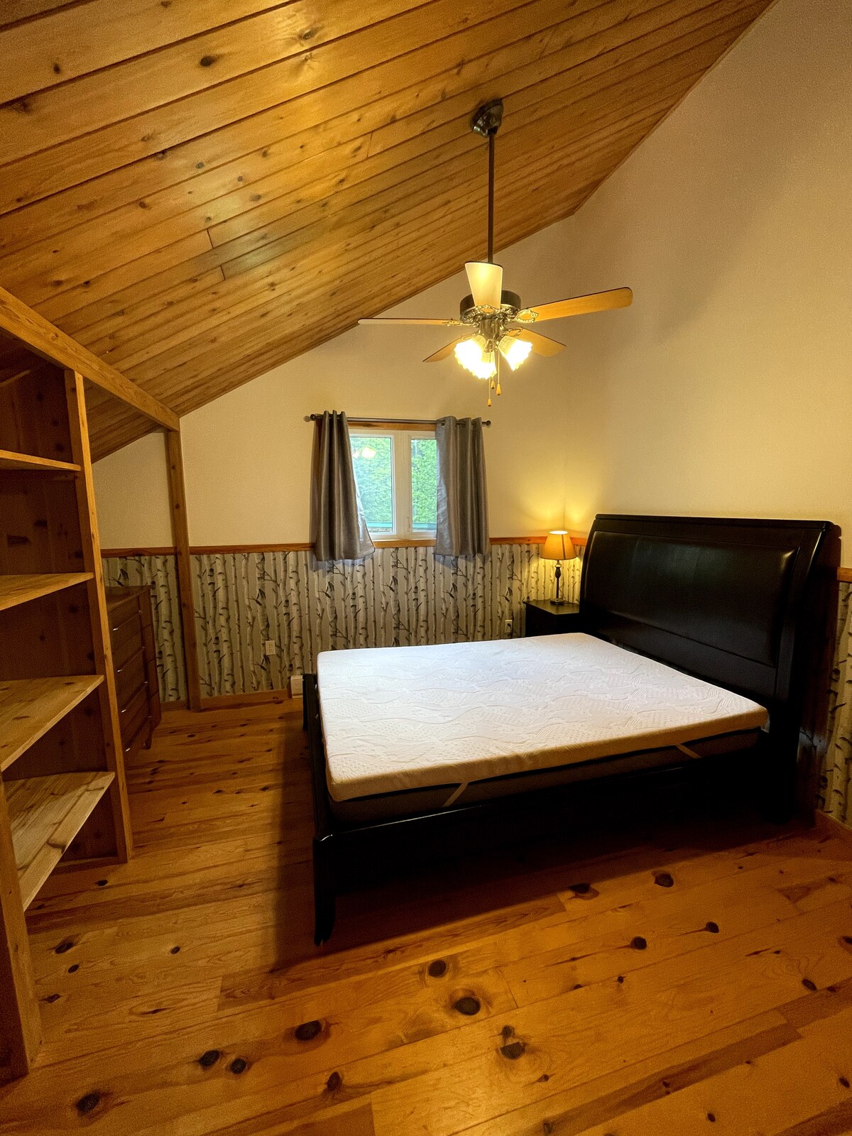 Chumba cha kulala cha ghorofa kilicho na kitanda aina ya queen na nafasi kubwa ya kuhifadhi.