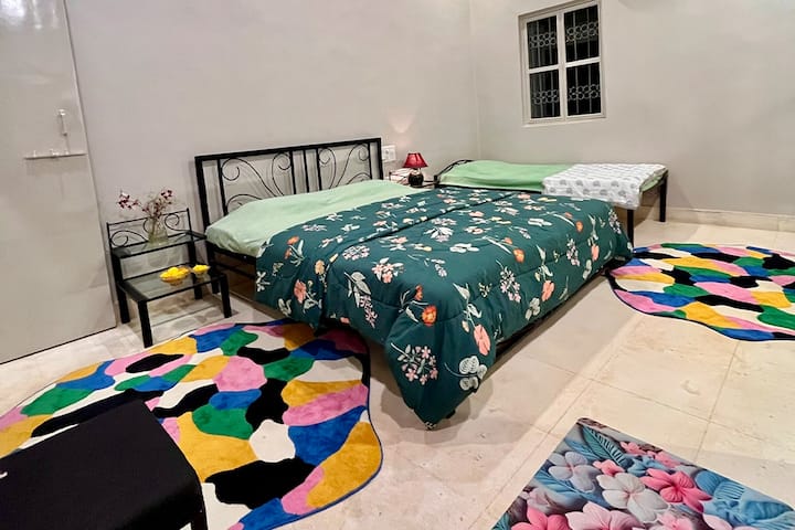 Enorme slaapkamer ingericht met tapijten en echte bloemen, uitgerust met airconditioning, 1 kingsize bed, 1 eenpersoonsbed, 2 extra vloermatrassen, samen met een dressoir en ruime kasten, compleet met gaas ramen balkon met uitzicht op de patio en tuin. 