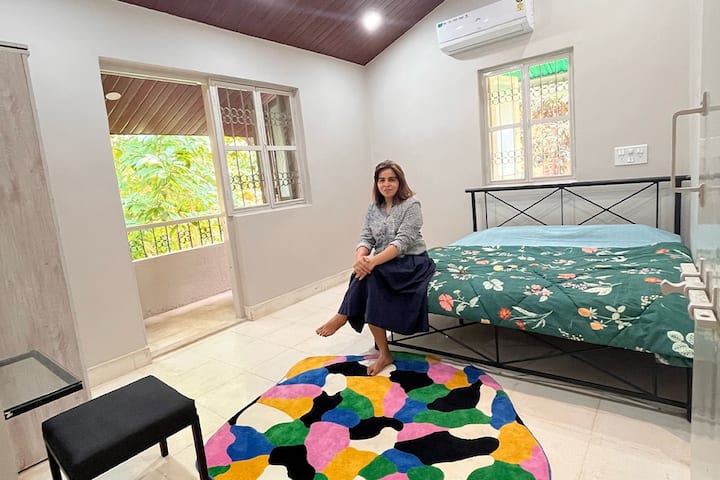 Slaapkamer ingericht met tapijten en echte bloemen, uitgerust met airconditioning, 1 kingsize bed, 2extra vloermatrassen, samen met een dressoir en kast, compleet met gaasramen en balkon met uitzicht op de tuin. 
