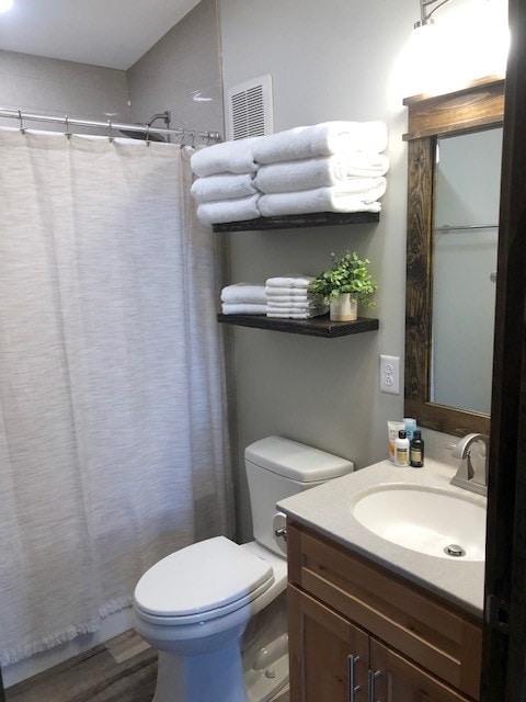A clean bathroom space showcases a white shower curtain and neatly arranged towels on wooden shelves. A modern sink area features a mirror above with minimalistic toiletries displayed nearby. The room is complemented by warm wood cabinetry and neutral-toned walls.