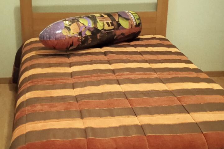 Jednolôžková izba s manželskou posteľou a polovičnými oknami.