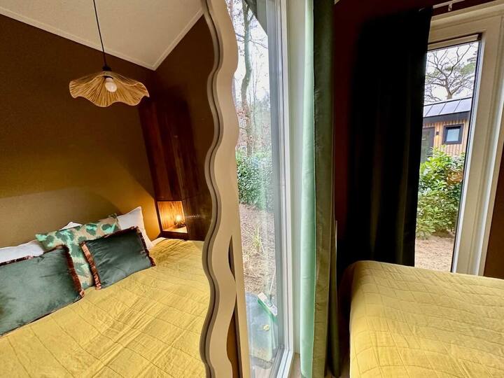 Slaapkamer met extra breed tweepersoonsbed en twee aparte dekbedden. Twee kasten voor spullen en kleding. Spiegel en kapstok met kledinghangers. Ramen met muggenhor en verduisterende gordijnen. Vanuit het bed uitzicht op de bomen en eekhoorns.