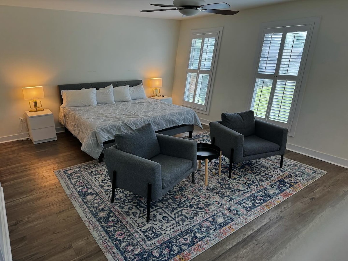 Luxurious 3rd floor bedroom featuring a king-size bed, 55” smart TV, dual lounging chairs, and a private bath with a soaking tub, separate shower, his and hers vanity, walk-in closet, and separate toilet room.