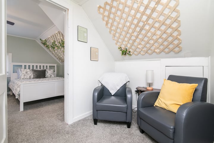 Ce coin salon confortable au troisième étage dispose d'un lit jumeau, de murs en treillis ornés de guirlandes et d'un accès facile à la salle de bain entière. C'est un espace de promenade menant à la charmante chambre Rose Garden