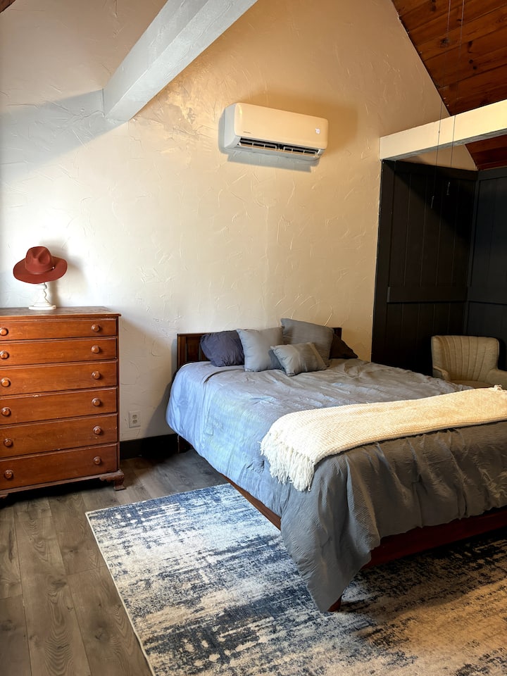 Manželská posteľ so sedacou stoličkou a komodami.