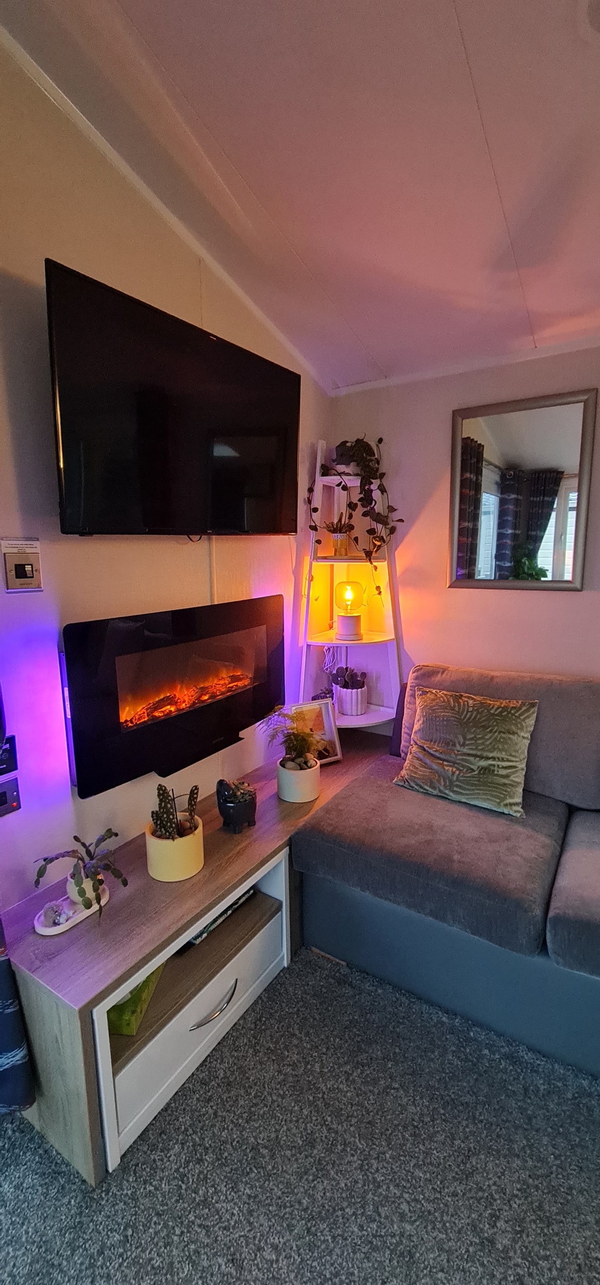 Sala de estar con chimenea eléctrica y TV. Sistema de sonido Bluetooth en el techo