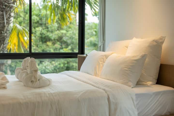 غرفة نوم تحتوي على سرير كبير ونافذة مع ستائر للخصوصية ومناشف جديدة لمزيد من الراحة والراحة.