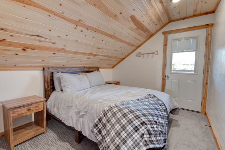 Cozy cabin bedroom with comfortable bed and rustic wood ceilings — the perfect place to rest after a day exploring Yellowstone and Island Park.