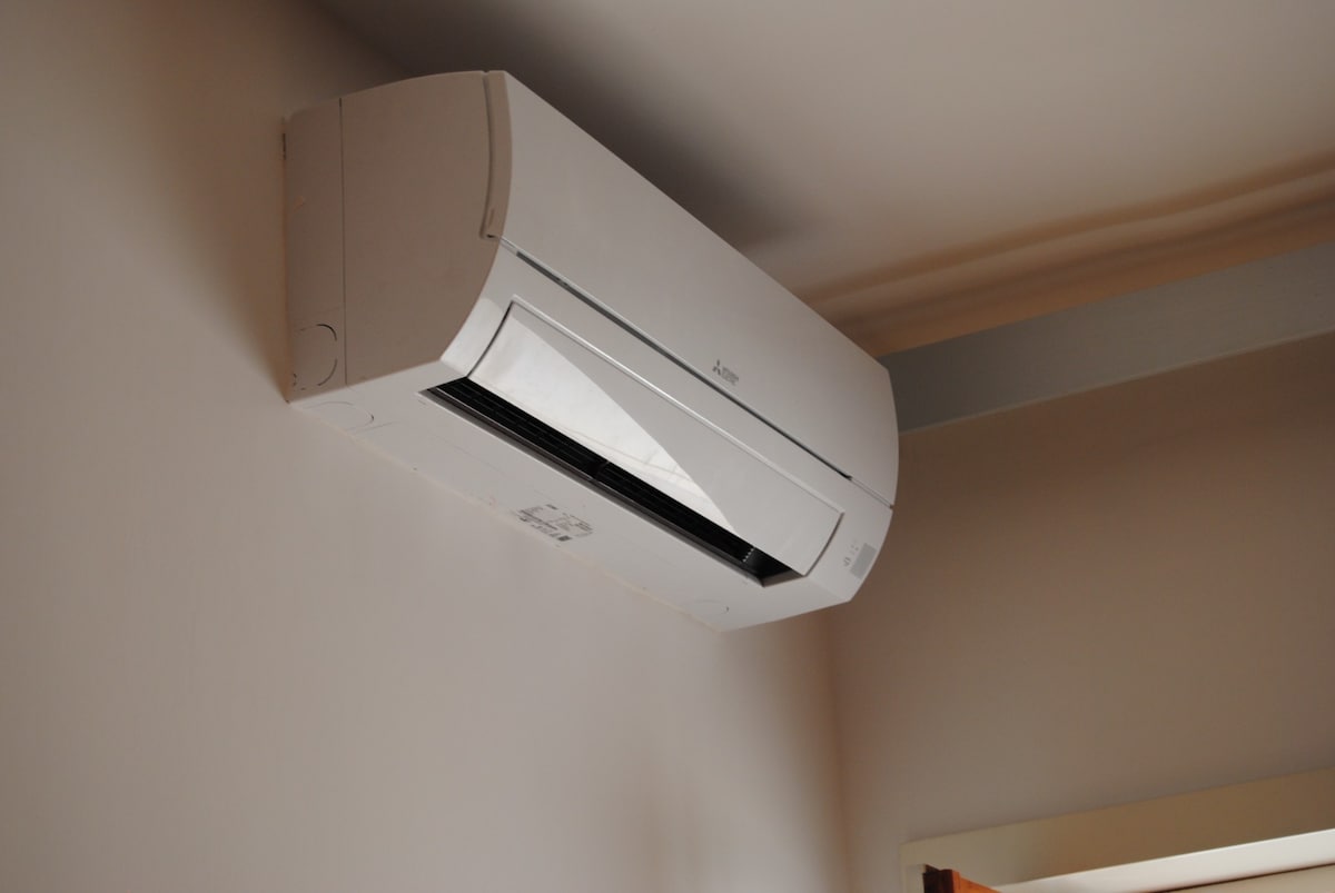 An air conditioning unit is mounted on a light-colored wall, providing temperature control for the space. The design is sleek and modern, blending seamlessly into the interior aesthetics.
