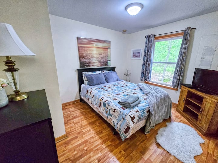 Queen size bed and TV. Room also features dresser and lamp. Located on 1st floor
