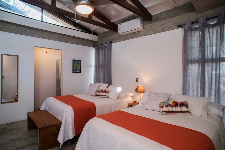 Este quarto está localizado na área do terraço, ao lado da piscina. É um quarto mais independente, já que fica fora da casa principal, mas ainda dentro da propriedade. Este quarto tem duas camas queen size e um banheiro privativo. 