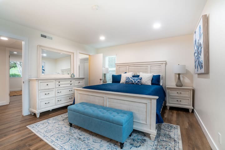 חדר השינה הראשי גדול למדי עם מיטת קינג סייז, 2 שידות לילה, שידה עם מראה ושידת מגירות גבוהה (לא נראית, מאחורי המצלמה).