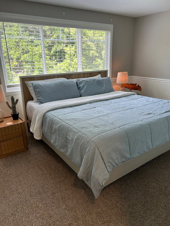 ห้องนอนพร้อมเตียงขนาดคิงไซส์ โต๊ะข้างเตียง เก้าอี้ และตู้เสื้อผ้า