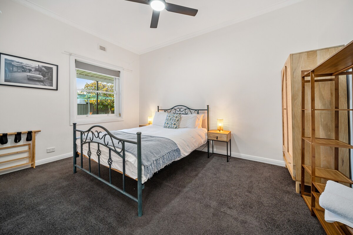 Prostrana spavaća soba s krevetom od kovanog željeza, blagom rasvjetom i mirnim ambijentom.