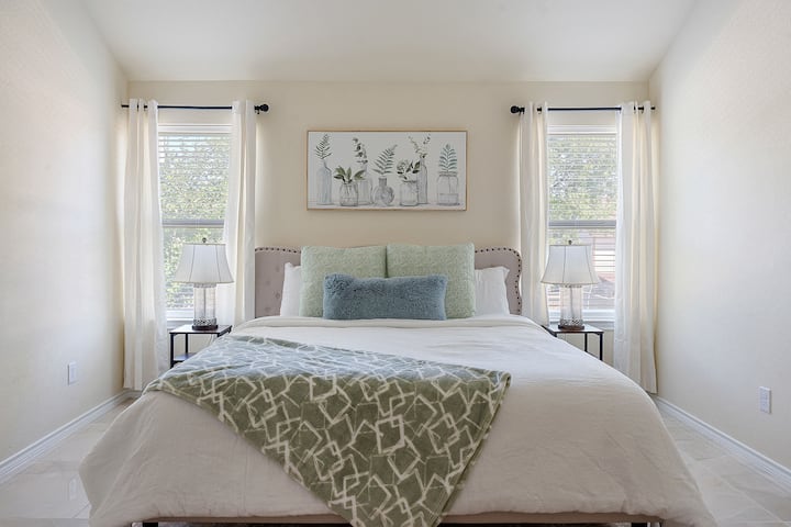 ก้าวเข้าสู่ห้องนอนที่เงียบสงบมีเตียงที่อบอุ่นโคมไฟข้างเตียงที่มีสไตล์และศิลปะบนผนังทางพฤกษศาสตร์ที่มีรสนิยม