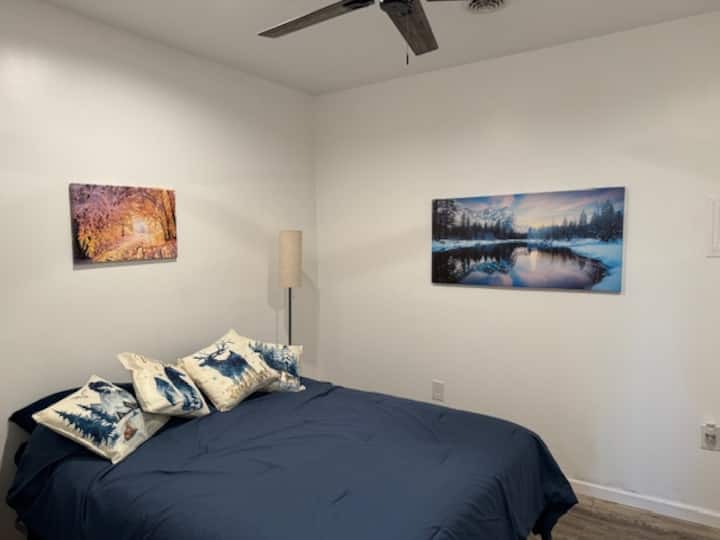 นี่คือห้องธีมฤดูหนาวเตียงควีนไซส์ 1 เตียงพร้อมโต๊ะข้างเตียงโคมไฟอ่านหนังสือพัดลมเพดานและตู้เสื้อผ้า โครงเตียงสูงพอที่จะเก็บสัมภาระไว้ใต้เตียงได้