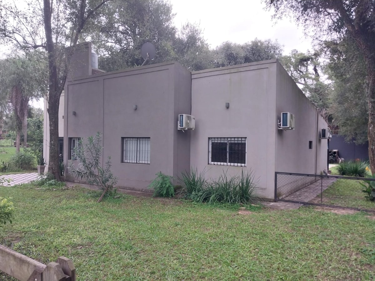 The exterior of a modern, two-story building is showcased, featuring large windows and strategically placed air conditioning units. Surrounding greenery enhances the natural setting, while the well-maintained lawn adds to the inviting ambiance of the space.