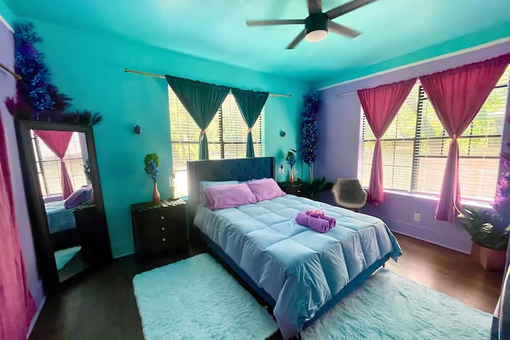 جناح الأحلام الساحرة: غرفة نوم رئيسية هادئة بألوان فيروزية وخزامى نابضة بالحياة وسرير بحجم كبير وفراش فاخر وتلفزيون وديكور غريب الأطوار.