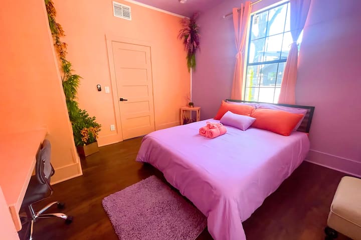 Sunset Grove: غرفة نوم مريحة مغطاة بالخوخ الدافئ وألوان الخزامى، مع مكتب ومكتب ومساحة خزانة وسرير بحجم كوين وفراش ناعم ومساحات خضراء مورقة.