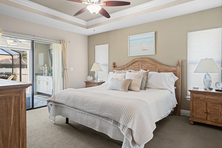 Chumba cha msingi chenye nafasi kubwa chenye kitanda cha kifalme, ufikiaji wa kando ya bwawa na mapambo ya pwani yenye kutuliza kwa ajili ya kahawa ya asubuhi au mapumziko ya usiku yenye utulivu.