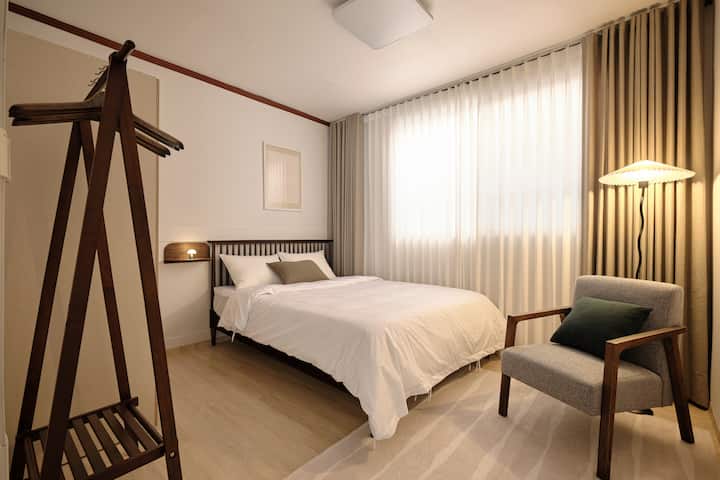 Hay una cama tamaño queen y ropa de cama de estilo hotel, e iluminación y sillas acogedoras.