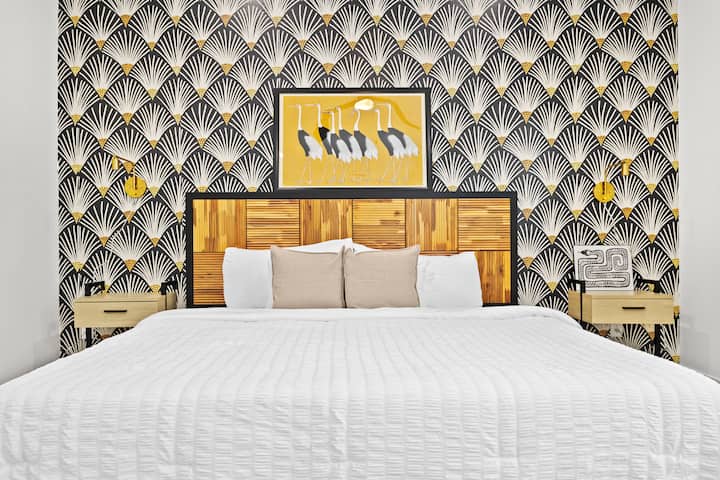 Chumba hiki kikuu cha kulala kina kitanda maridadi, ukuta mkali wa kijiometri na mapazia ya haradali. Inatoa mwanga mwingi wa asili, meza za kisasa, feni ya dari na ufikiaji wa moja kwa moja kwenye baraza kwa ajili ya maisha rahisi ya ndani na nje.