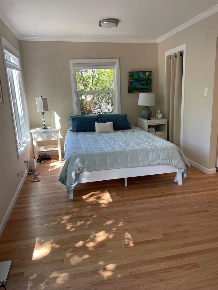 Chumba cha kulala cha msingi kinachoelekea magharibi chenye sakafu mpya nyekundu za mwaloni