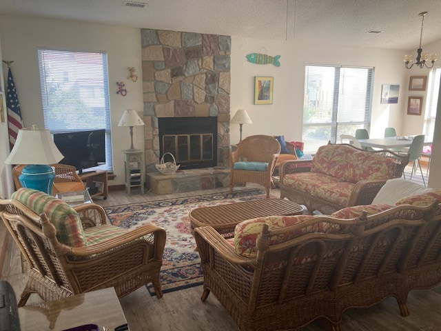 A spacious living area features a stone fireplace as a focal point, complemented by comfortable wicker seating and colorful cushions. Large windows allow natural light to fill the room, showcasing a patterned area rug that adds warmth and texture to the space.