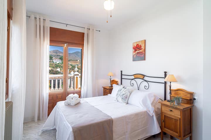 Dormitorio con cama de matrimonio y acceso al balcón.