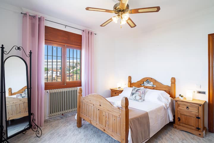 Dormitorio con cama de matrimonio y ventilador de techo.