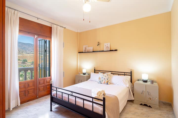 Dormitorio con cama de matrimonio y acceso al balcón.