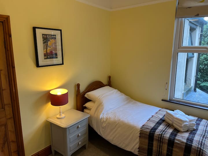 Aan de achterkant van het huis is er een eenpersoonskamer met uitzicht op de parkbomen vanuit het raam.