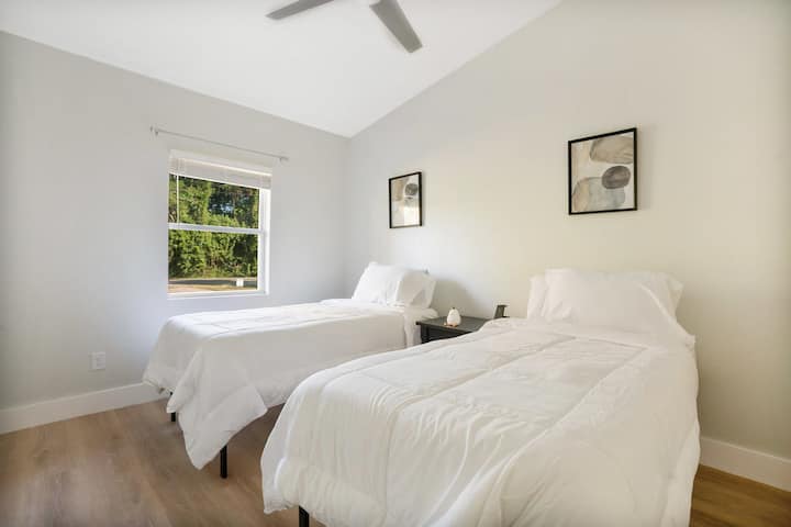 Bright and inviting, this white bedroom features two cozy double beds, soft linens, and windows that let in plenty of natural light, ideal for families or friends looking to relax and recharge in comfort.