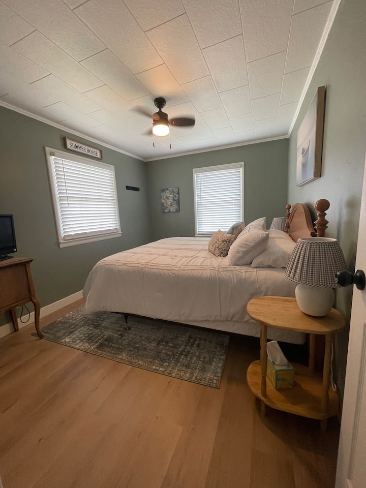 De grote slaapkamer - met een kingsize bed - vult zich met natuurlijk licht, gelegen in de zuidoostelijke hoek van het huisje, met uitzicht op Webster Lake.  