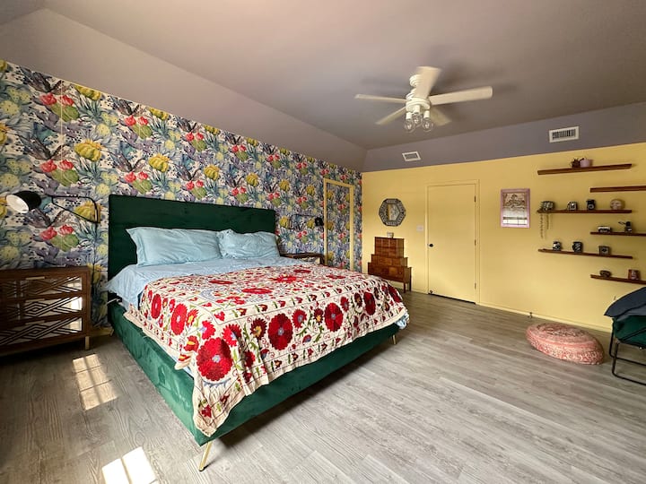 Cette chambre principale spacieuse dispose d'un lit king size confortable, d'un mur d'accent floral vibrant et d'une décoration élégante. Il peut accueillir 2 personnes et comprend une salle de bain attenante et un dressing, idéal pour un séjour reposant et relaxant.