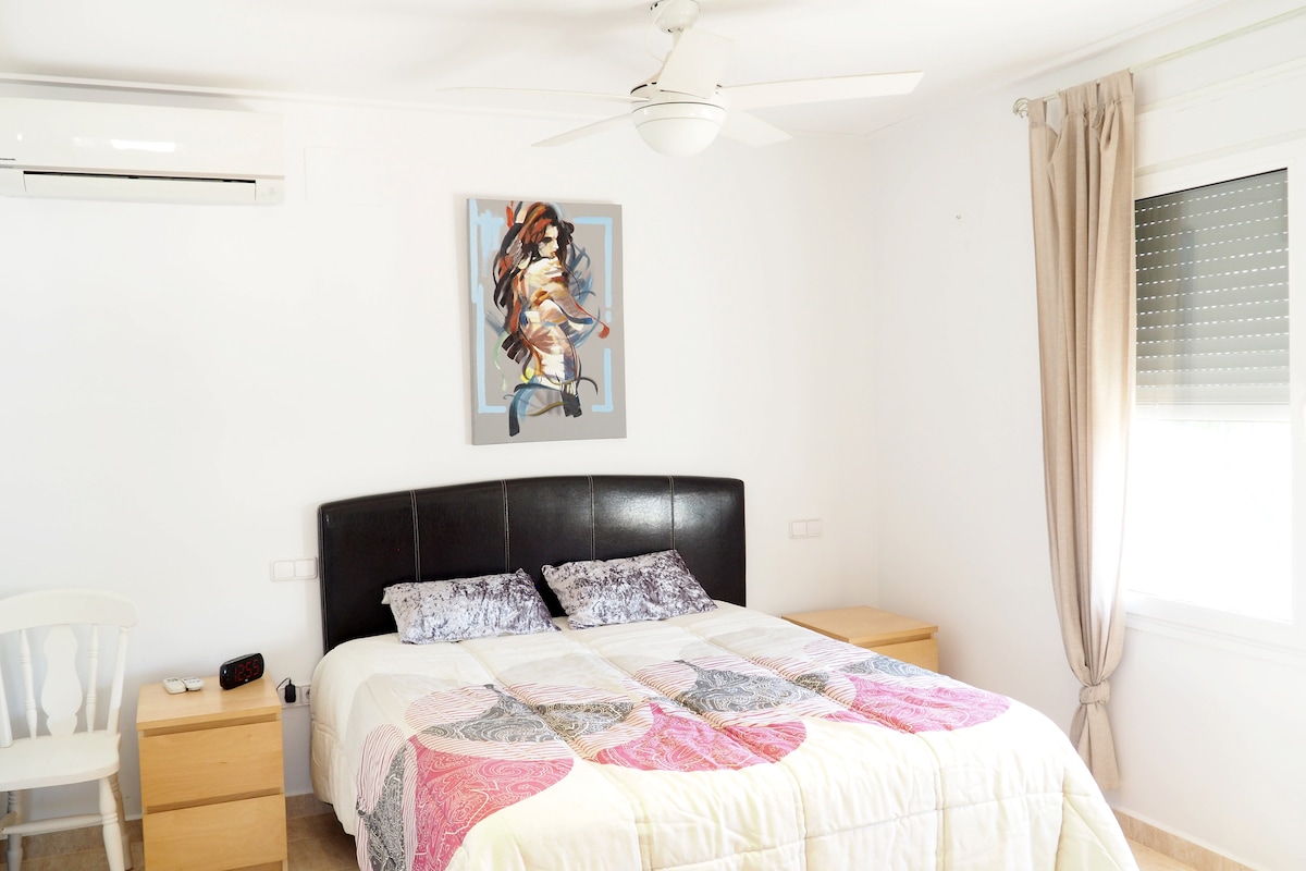 Dormitorio de matrimonio con despacho, baño en suite, aire acondicionado y ventilador de techo en la primera planta.