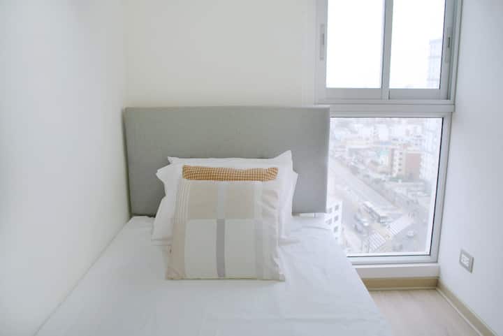 Уютна стая с удобно легло и прозорец, която предлага панорамна гледка към града, идеална за почивка и релаксация.





