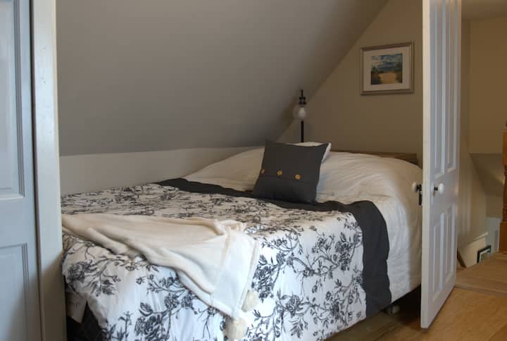 Een van de twee slaapkamers op de bovenverdieping, queensize bed, bureau, tv, grote kast en dressoir.