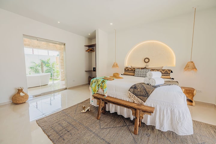 Kamar tidur utama dilengkapi tempat tidur berukuran king, 55'' LG Smart Television, lemari, dan kamar mandi dalam dengan bak mandi yang menghadap ke oasis hijau.