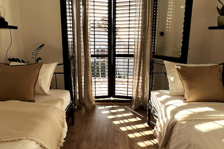 第二间卧室配有两张单人床、空调和阳台，配有两把椅子和桌子，可欣赏花园的美景。