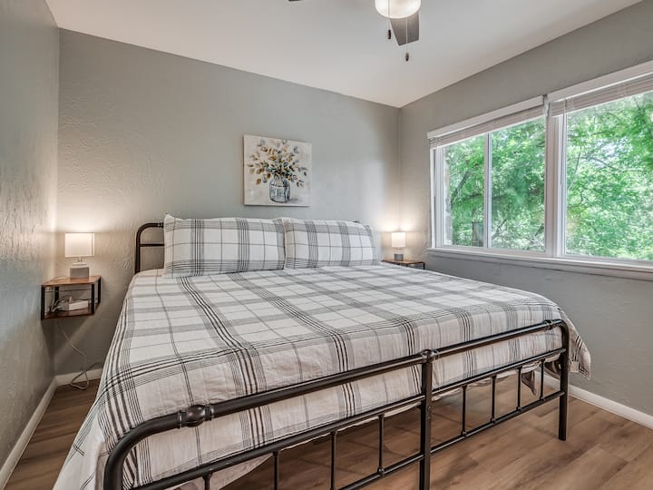 Cette chambre king-size comprend des barres d'alimentation, des lampes et des tables de chevet des deux côtés du lit, ainsi qu'une petite commode, un placard, un miroir pleine longueur, un ventilateur de boîte et des draps et oreillers supplémentaires.