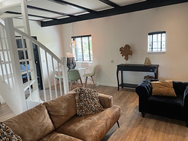 A living area is visible, featuring a spacious brown couch adorned with decorative pillows. A black console table rests against the wall, and a dining table with modern chairs is positioned near a window with multiple panes, allowing natural light to flow in.